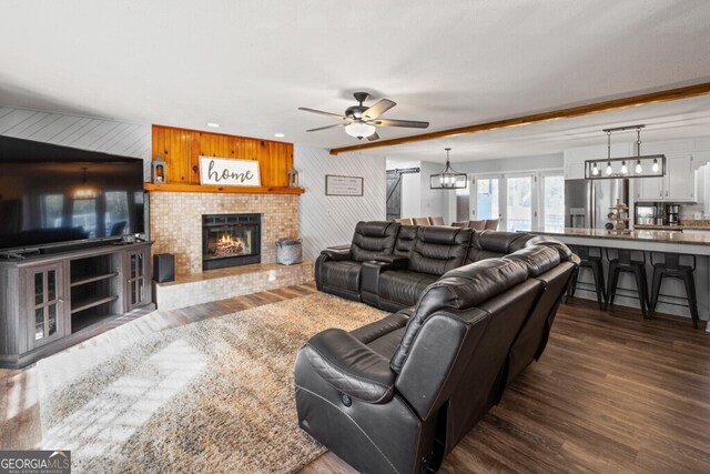 living room with dark hardwood / wood-style flooring, ceiling fan with notable chandelier, and wood walls