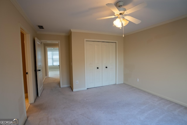 unfurnished bedroom with ceiling fan, a closet, light carpet, and crown molding