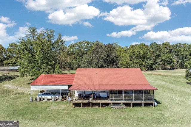 exterior space featuring a sunroom, a carport, and a lawn