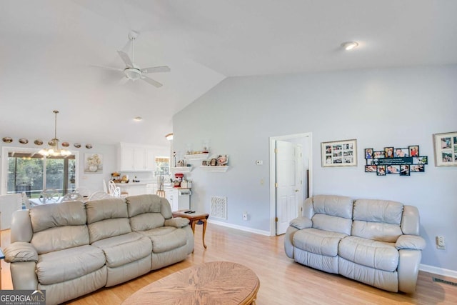 living room featuring lofted ceiling, ceiling fan with notable chandelier, and light hardwood / wood-style flooring