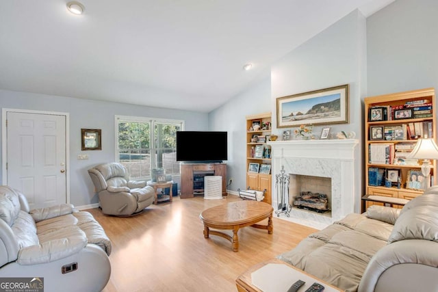 living room featuring light wood-type flooring, a premium fireplace, and lofted ceiling