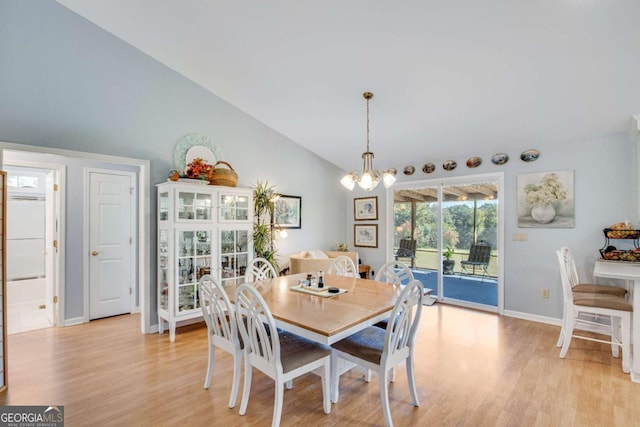 dining room with light wood-type flooring, an inviting chandelier, and high vaulted ceiling