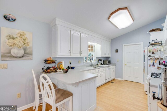 kitchen featuring kitchen peninsula, a breakfast bar area, white appliances, light wood-type flooring, and white cabinets