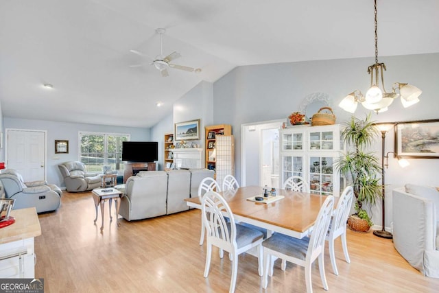 dining area featuring vaulted ceiling, light hardwood / wood-style floors, and ceiling fan with notable chandelier