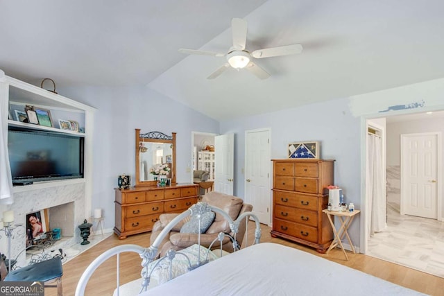 bedroom with ceiling fan, vaulted ceiling, and light wood-type flooring