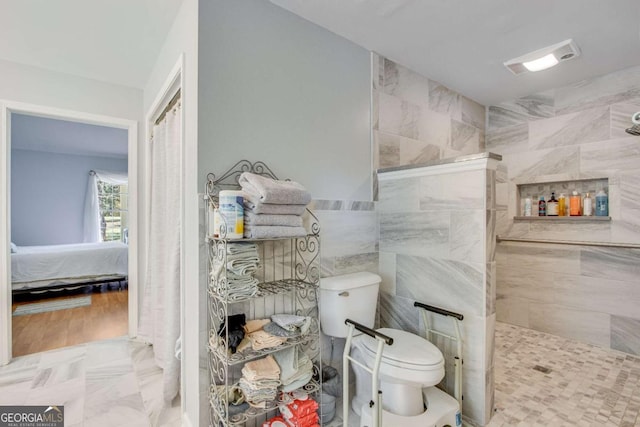 bathroom featuring walk in shower, tile walls, and toilet