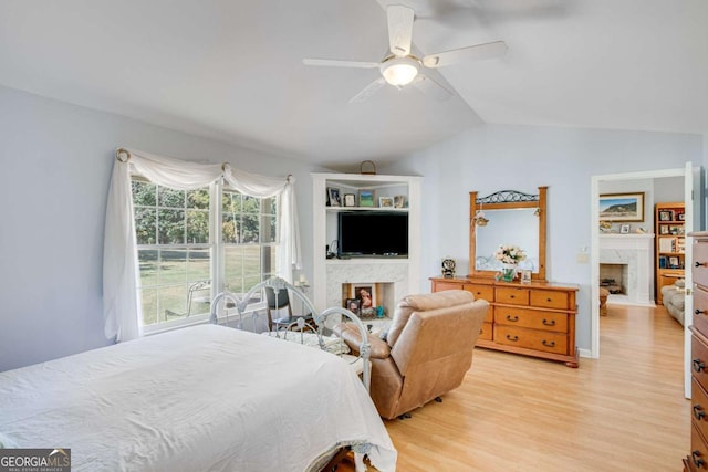 bedroom with vaulted ceiling, ceiling fan, light hardwood / wood-style floors, and a fireplace