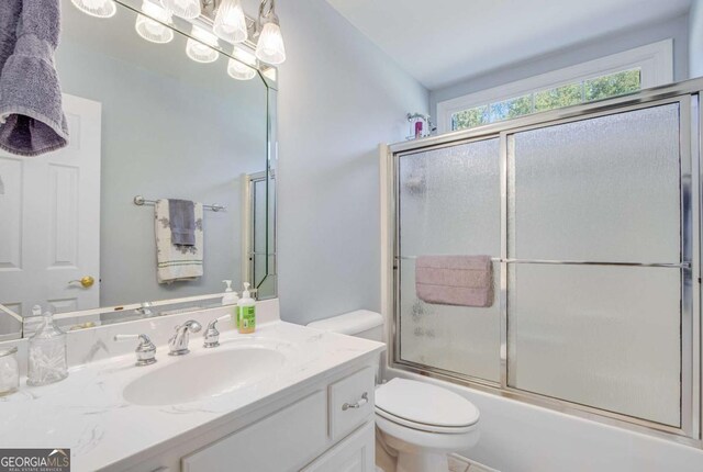 full bathroom with toilet, enclosed tub / shower combo, and vanity