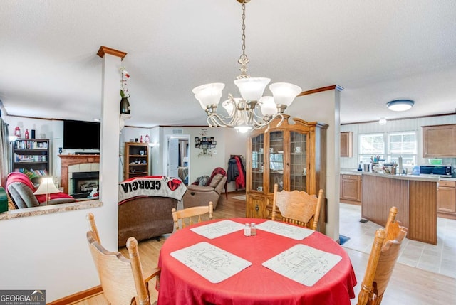 dining area featuring a textured ceiling, a chandelier, crown molding, and light hardwood / wood-style flooring