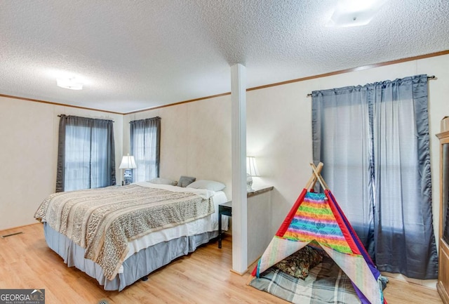 bedroom with a textured ceiling, ornamental molding, and hardwood / wood-style flooring