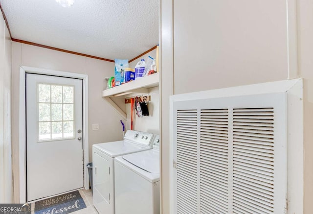 clothes washing area with a textured ceiling, light tile patterned floors, washer and dryer, and crown molding