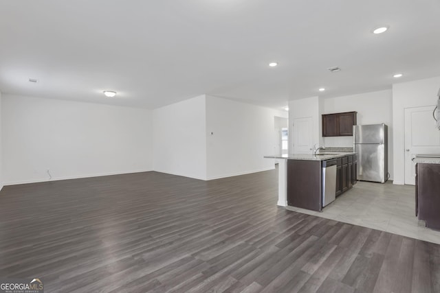 kitchen featuring sink, hardwood / wood-style flooring, a kitchen island with sink, and appliances with stainless steel finishes