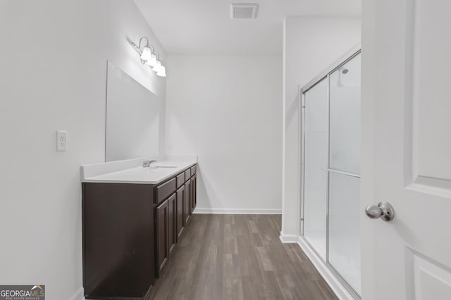 bathroom featuring wood-type flooring, vanity, and a shower with shower door