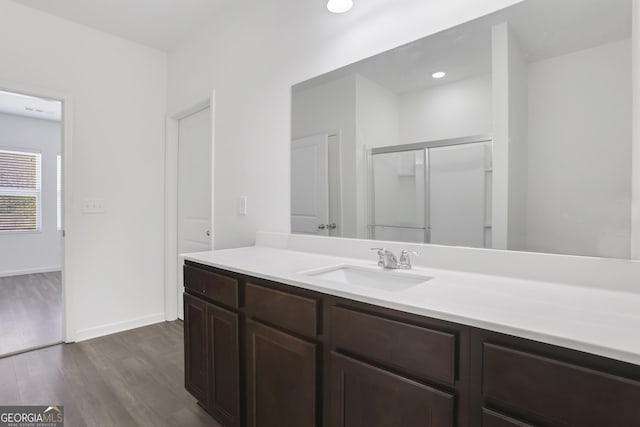 bathroom with hardwood / wood-style flooring, vanity, and a shower with door