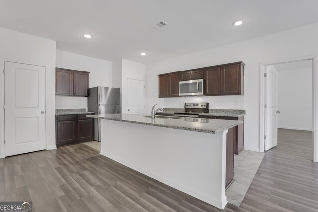 kitchen with a center island with sink, dark brown cabinets, and stainless steel appliances