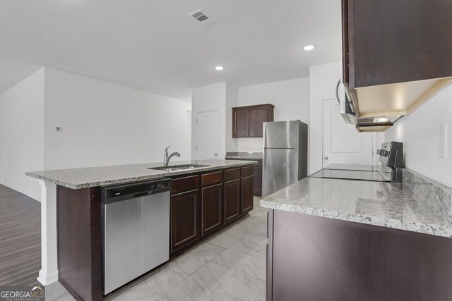 kitchen with appliances with stainless steel finishes, light stone countertops, and dark brown cabinets