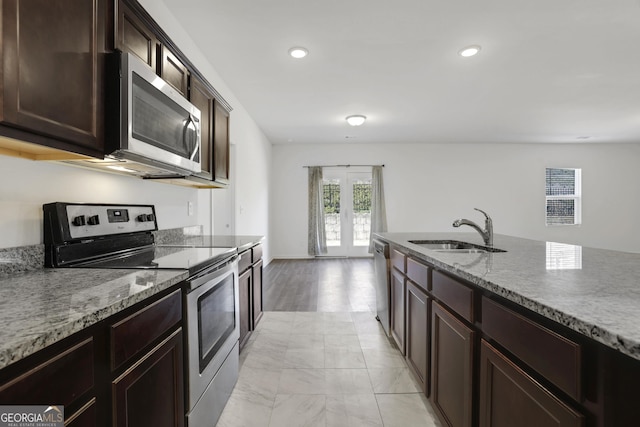 kitchen featuring sink, stainless steel appliances, light stone counters, dark brown cabinetry, and french doors