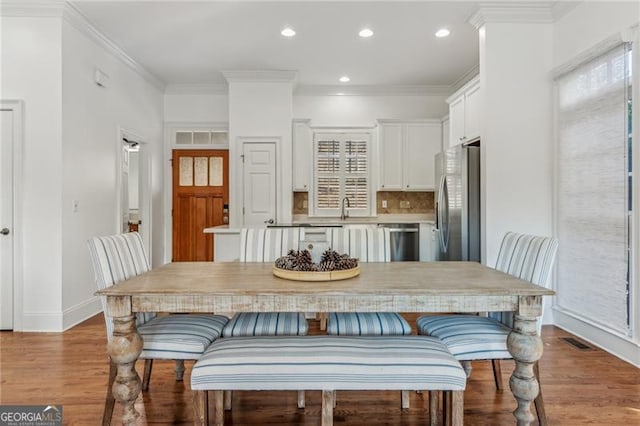 dining space with light wood-type flooring, sink, and crown molding