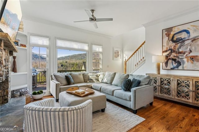 living room with dark wood-type flooring, ornamental molding, a fireplace, and ceiling fan