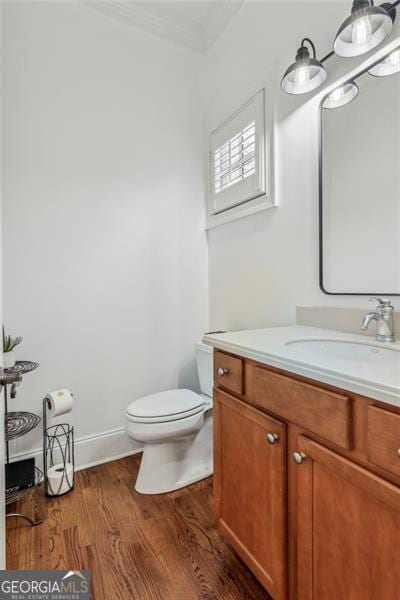 bathroom with toilet, vanity, and wood-type flooring