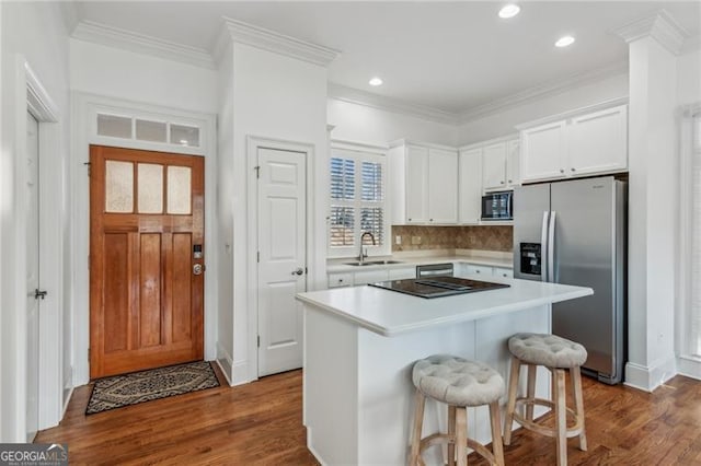 kitchen featuring a kitchen island, white cabinetry, black microwave, sink, and stainless steel fridge