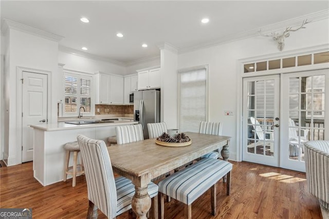 dining room with sink, light hardwood / wood-style flooring, crown molding, and french doors