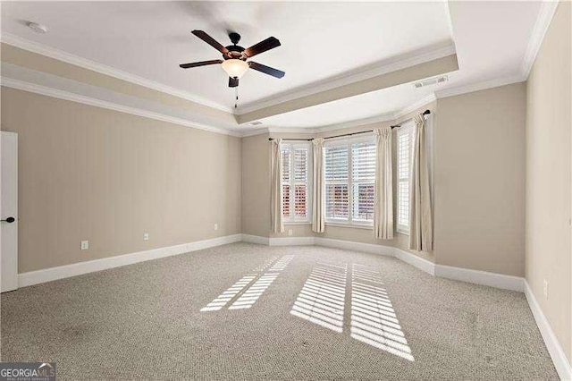 empty room featuring a raised ceiling, light carpet, ornamental molding, and ceiling fan