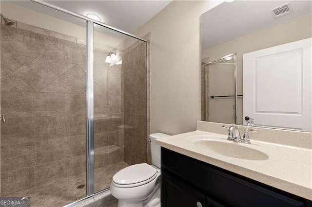 bathroom featuring toilet, vanity, and a shower with door