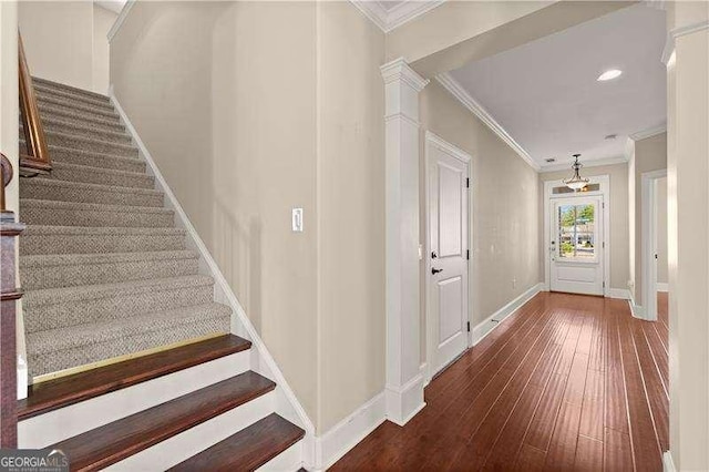 stairs with crown molding, hardwood / wood-style floors, and decorative columns