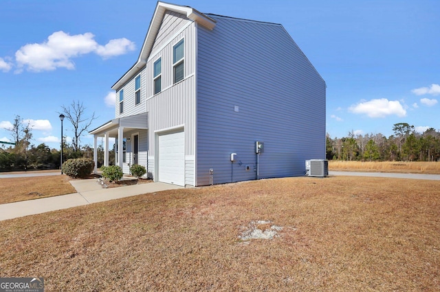 view of home's exterior with a garage, a yard, central AC unit, and a porch