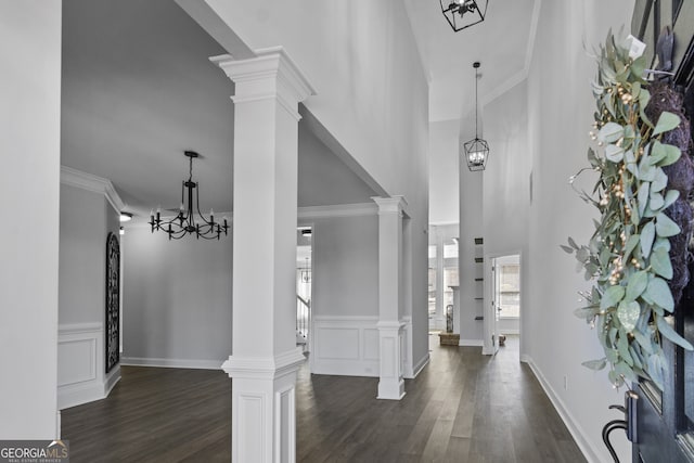 foyer with decorative columns, dark wood-type flooring, and a notable chandelier