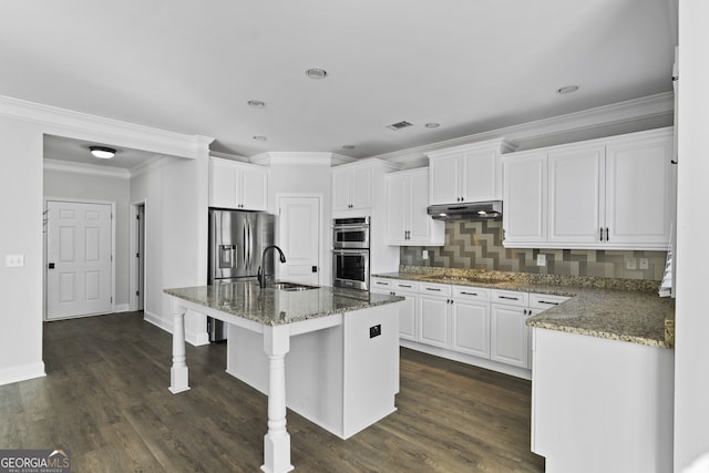 kitchen featuring a center island with sink, decorative backsplash, dark stone countertops, white cabinets, and sink