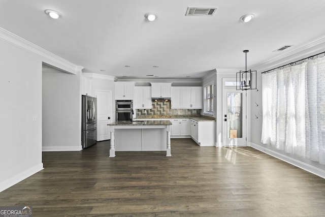 kitchen with backsplash, a kitchen island, white cabinetry, appliances with stainless steel finishes, and ornamental molding