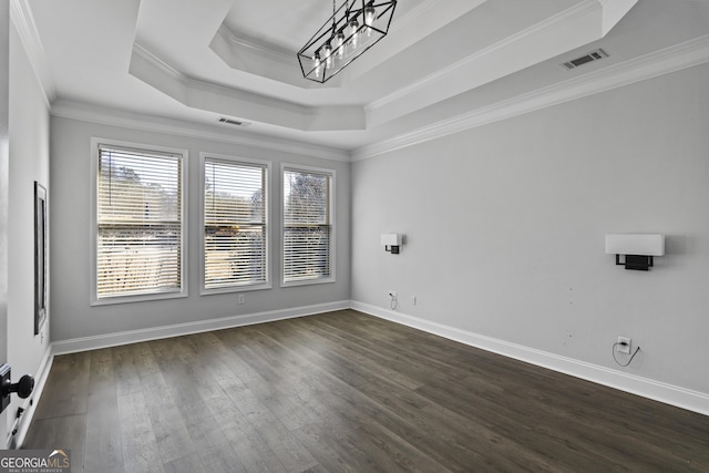 empty room with crown molding, dark hardwood / wood-style floors, a raised ceiling, and a notable chandelier