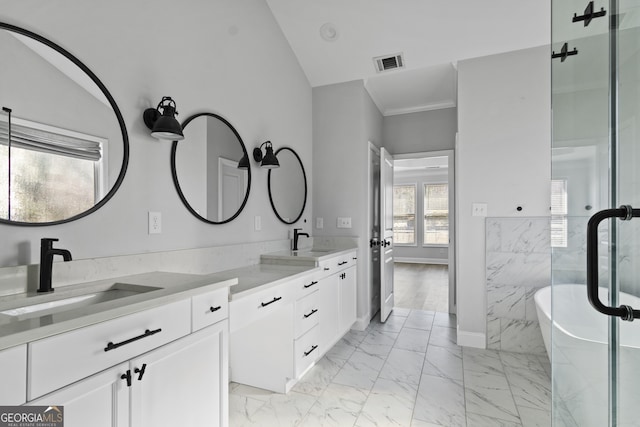 bathroom with ornamental molding, lofted ceiling, a tub to relax in, and vanity