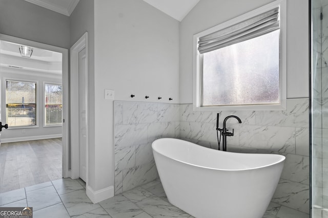 bathroom with a washtub, crown molding, and lofted ceiling