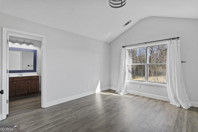 empty room with hardwood / wood-style flooring, sink, and lofted ceiling