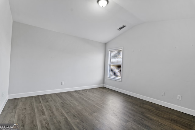 spare room featuring dark hardwood / wood-style flooring and lofted ceiling