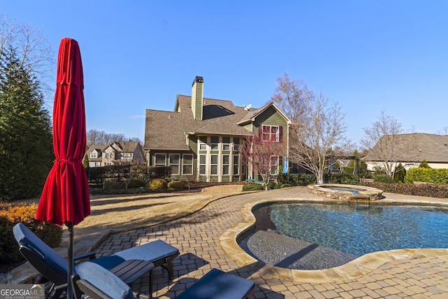 view of pool featuring an in ground hot tub, a patio area, and a sunroom