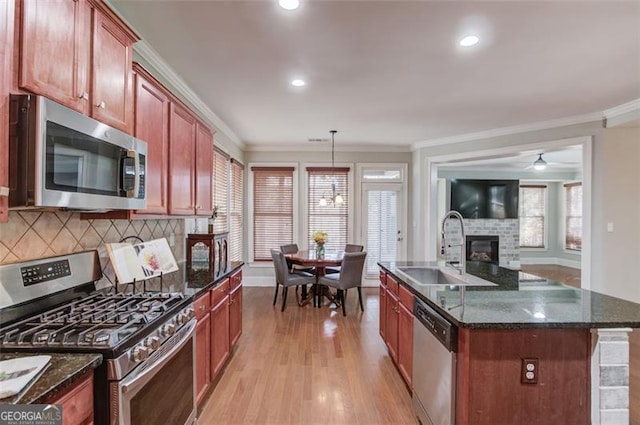 kitchen featuring pendant lighting, stainless steel appliances, an island with sink, light hardwood / wood-style floors, and sink