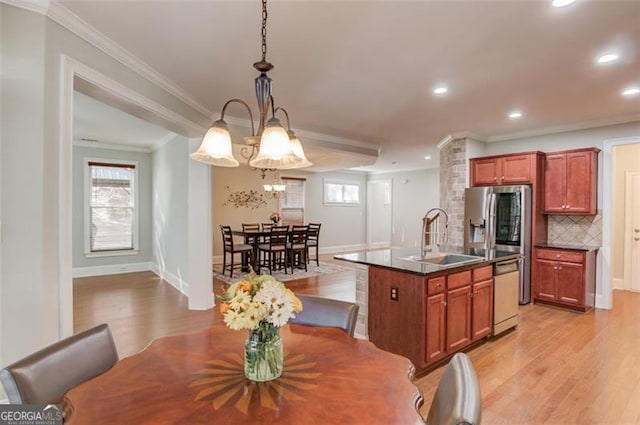 kitchen featuring decorative light fixtures, an inviting chandelier, sink, stainless steel dishwasher, and a center island with sink