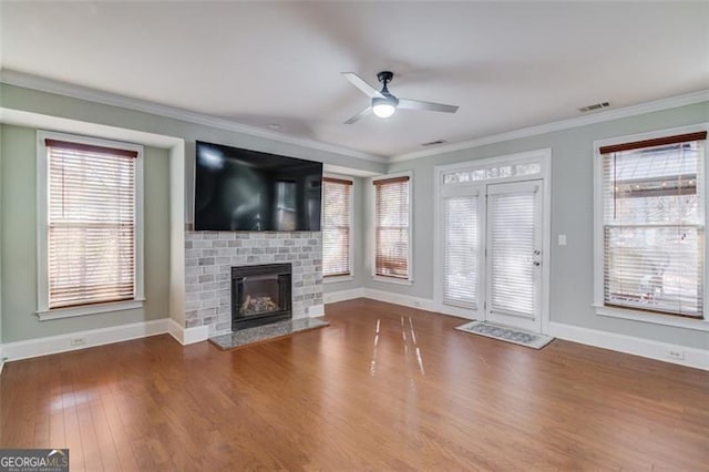 unfurnished living room featuring ceiling fan, hardwood / wood-style flooring, crown molding, and a fireplace