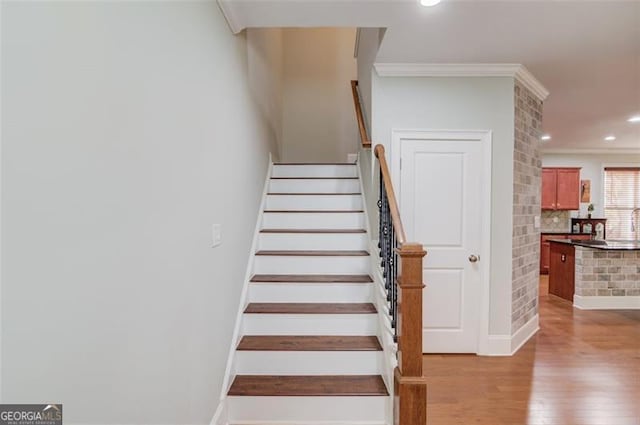 staircase featuring ornamental molding and wood-type flooring