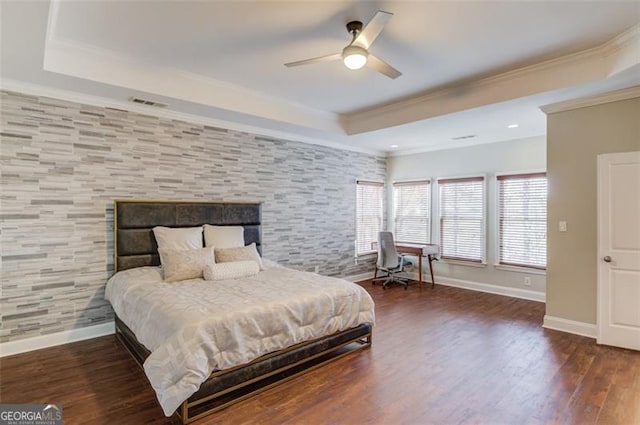 bedroom featuring ceiling fan, dark wood-type flooring, crown molding, and a tray ceiling