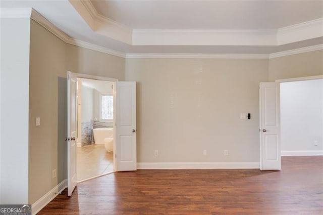 spare room with a raised ceiling, dark hardwood / wood-style floors, and crown molding