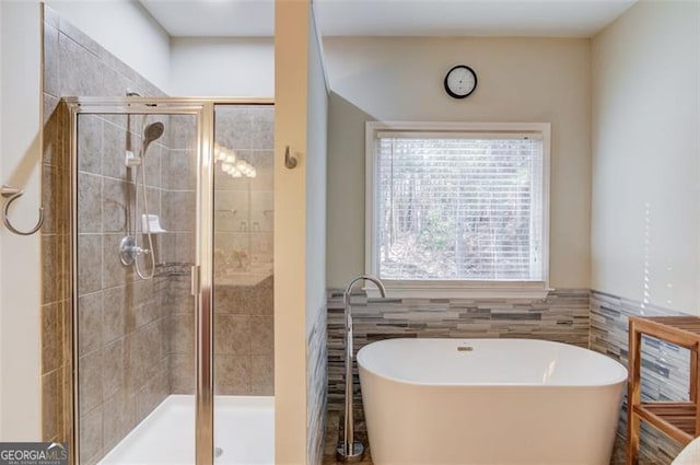 bathroom with shower with separate bathtub and tile walls