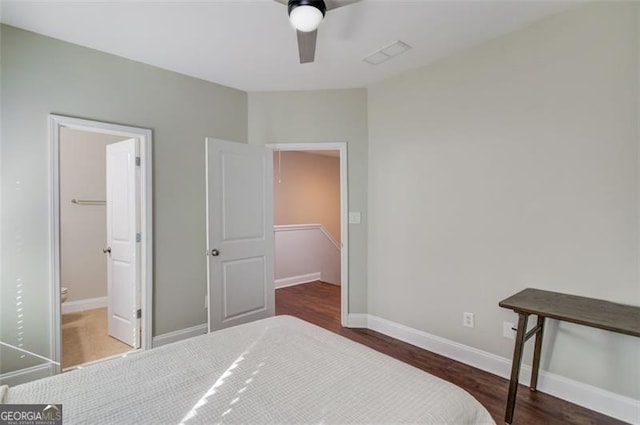 bedroom featuring ceiling fan, dark hardwood / wood-style floors, a spacious closet, and ensuite bath