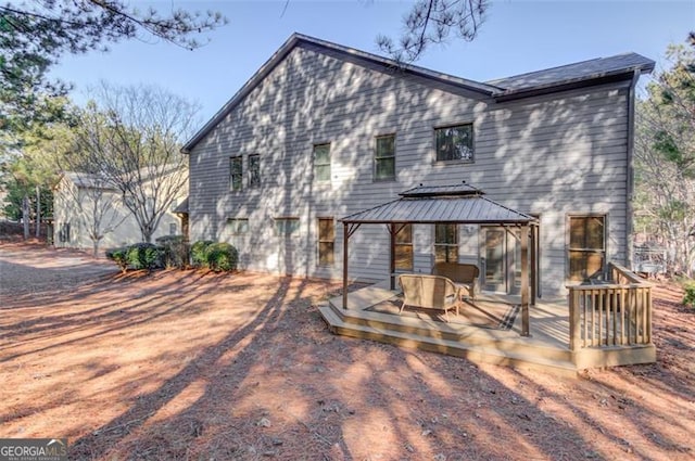 rear view of property with a deck and a gazebo