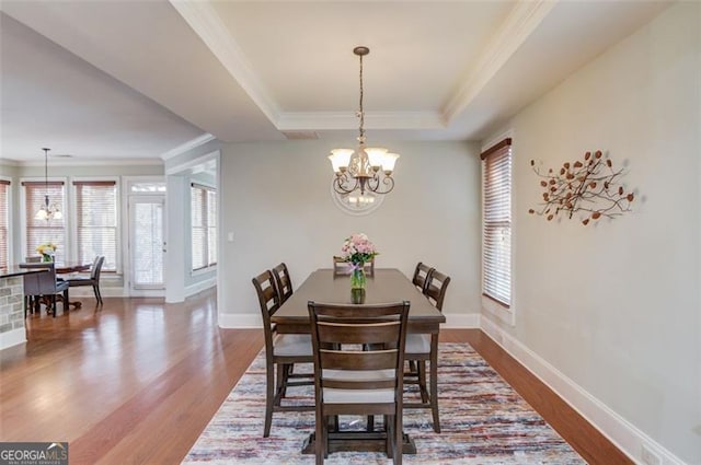 dining space featuring a raised ceiling, plenty of natural light, hardwood / wood-style flooring, and a notable chandelier