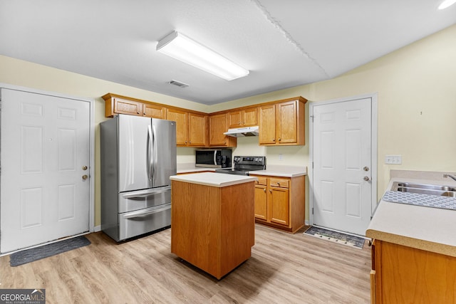 kitchen with light wood-type flooring, appliances with stainless steel finishes, a kitchen island, and sink